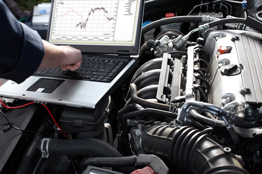 Mecânico utilizando notebook com scanner automotivo para diagnóstico técnico do câmbio automático